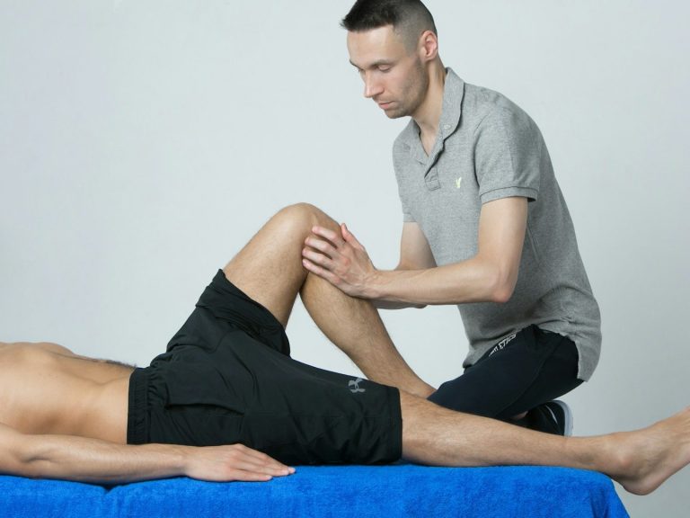 Fisioterapeuta realizando un tratamiento a domicilio en la pierna de un paciente.