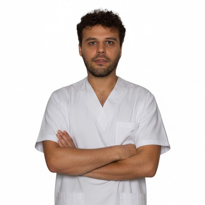 Fisioterapeuta con bata médica cruzando los brazos, fondo blanco.