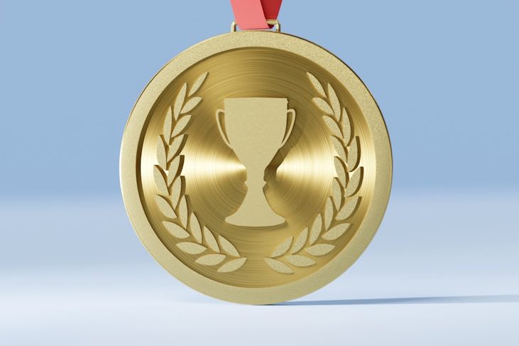 Medalla dorada con un trofeo en el centro, rodeada de hojas de laurel.
