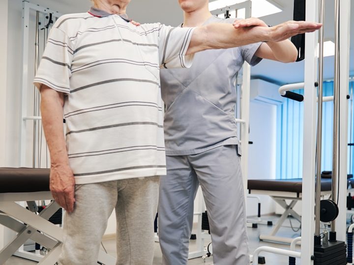 Un hombre mayor realiza ejercicios de rehabilitación con la ayuda de un fisioterapeuta.