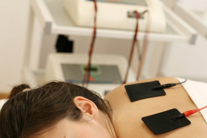 Mujer recibiendo tratamiento de electroterapia en la espalda.
